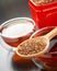 Rooibos in wooden spoon closeup, two tea cups and tea tin box