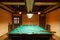 Room billiards decorated in dark wood with low lamps, billiard table with green cloth