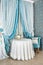 Room, blue and white curtains, table, armchair