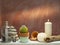 Room decoration with candles, rocks, bottle with black sand and cactus on white shelf against old brick color wall