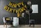 Room interior with gift boxes and phrase HAPPY BIRTHDAY made of balloon letters