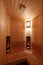 A room in a sauna lined with wood with a soft light of a wall lamp