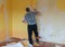 A room where a man cleans a wall, removing old wallpaper, washing a wall, repair concept