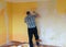 A room where a man cleans a wall, removing old wallpaper, washing a wall, repair concept