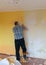 A room where a man cleans a wall, removing old wallpaper, washing a wall, repair concept