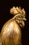 The rooster`s head is made of yellow bronze isolated on a black background.