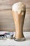 Root beer float in a tall pilsner glass, with vanilla ice cream melting, shown with thumb press disher.