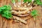 Roots of young horseradish on a wooden background.