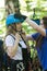 Rope adventure - a woman instructor puts on the insurance helmet on a head of young woman