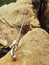 Rope end anchored for climbers into sandstone rock. Iron twisted rope fixed with srew clamps in block. Safety footpath between