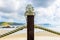 Rope fence on wooden pillar with glass lamp on beach.