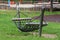 Rope hammock swing enforced with strong wooden and metal support made for climbing and relaxing in local public park surrounded