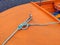 Rope moored in bow of orange boat. Mooring yacht rope with a knotted end tied around a cleat. Nautical accessories concept