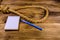 Rope with noose for the suicide, blank notepad and pen on wooden background