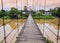 Rope suspension bridge across a river in flood, Thailand