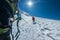 Rope team ascending Mont Blanc Monte Bianco summit 4,808m dressed red mountaineering clothes walking by snowy slopes with