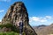 Roque Agando - Woman with backpack standing in front of massive volcanic rock formation Roque de Agando on La Gomera