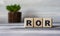 ROR - word on wooden cubes against the background of a light board with beautiful divorces and a cactus