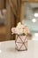 Rose buds and cloves in a geometric stand. Metal vase for decor. Little elegant detail of wedding decoration