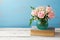Rose flower bouquet in vase on old books over wooden background