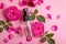 Rose fragrance spray with pink fresh flowers and petals on pink background