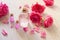 Rose oil in glass bottles and rose flower petals on white wooden background