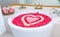 rose petals and leelawadee with heart shape decoration in bathtub and two towel, soap, shampoo, hair cream near bathtub