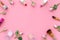 Rose, pink decorative cosmetics frame. Lipstick, bulk, eyeshadow and small rose flowers on pink background top view copy