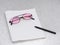 Rose pink tinted glasses with notebook and pen, for writing. Dyslexia, visual stress or optimistic outlook.