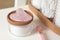 Rose quartz gua sha tool, natural face roller and toiletries on white shelf, closeup