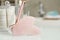 Rose quartz gua sha tool, natural face roller and toiletries on white table in bathroom, closeup. Space for text