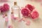 Rose water or oil bottles on wooden white background. Beautiful pink flowers and petals, aromatherapy and SPA concept