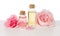 Rose water and oil in glass bottles and pink flowers isolated on white background