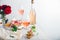 Rose wine in different wineglasses, bottle on white table with grapes cheese, snacks bouquet of flowers. modern still life Rose