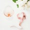 Rose wine in glass, pink decorative ribbon over white table