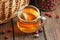 Rosehip brewed tea in a glass cup with red berry near on wooden rustic table, natural remedy and support for heart disease, diabet