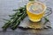 Rosemary herbal tea in a glass cup with fresh green rosemary herb on rustic wooden background.