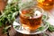 Rosemary tea in glass tea cup on rustic wooden table closeup. Herbal vitamin tea