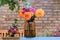 Roses, asters, dahilia in glass vase in the garden on the background of a brick wall. Sunny day. Floristic design