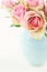 Roses in a light blue vase on cream beige shabby chic background