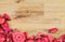 Roses petals on natural wooden table background. Love template for valentines day pink flowers at the bottom. Empty top.