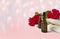 Roses, towel, essential oil bottle on pink background.