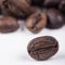 Rosted brown coffee beans lying on white background, selective focus