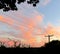 Rosy clouds crowd blue sky as silhouettes stand by