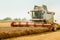 Rotary straw walker cut and threshes ripe wheat grain. Man in combine harvesters with grain header, wide chaff spreader