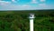 Rotating aerial shot of a high watching tower with forest trees around under blue cloudy sky