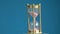 Rotating on blue background hourglass sand-glass with pink sand motion