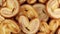 Rotating close up of fresh palm puff pastry in the shape of a heart. French biscuits with elephant ears. View from above. Close-up