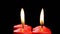 Rotating four red candles burning fire slowly spinning on a black background