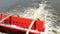 Rotating red paddle wheel of a cruise boat in motion with zoom in.